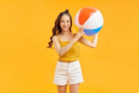 Photo for Young Asian girl with inflatable ball on vivid yellow background - Royalty Free Image