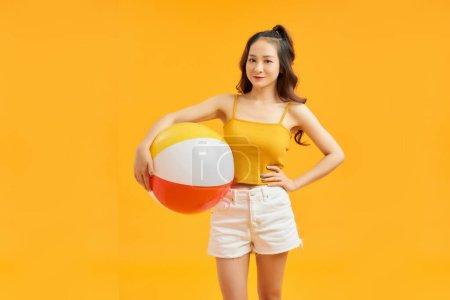 Photo for Young asian woman holding beach ball isolated on vivid yellow background happy - Royalty Free Image