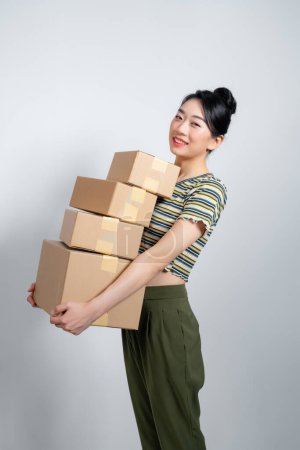 Téléchargez les photos : Belle jeune femme tient des boîtes en carton sur fond gris. - en image libre de droit