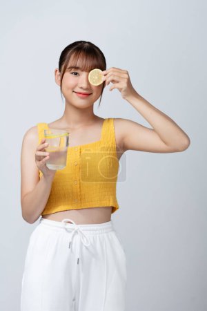 Photo for Young woman holding lemon slice in front of eye - Royalty Free Image