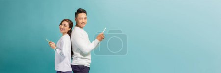 Photo for Image of asian couple holding smartphones, isolated on blue background - Royalty Free Image
