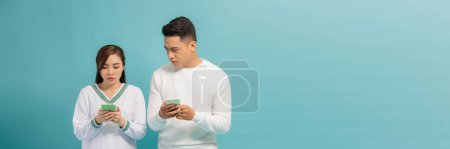 Téléchargez les photos : Asiatique jeune homme espionnage à petite amie messagerie texte à travers les smartphones - en image libre de droit