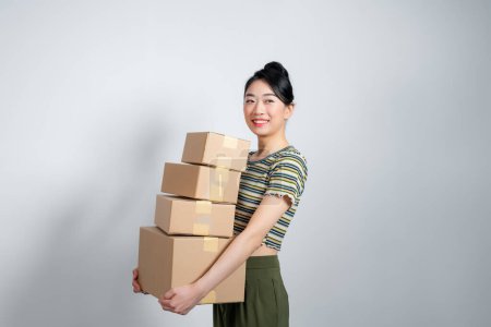 Photo for Happy asian woman holding pile of boxes, concept of delivery, shopping or business, white background - Royalty Free Image