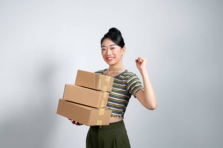 Foto de Mujer joven sosteniendo cajas celebrando la victoria y el éxito muy emocionada con el brazo levantado - Imagen libre de derechos