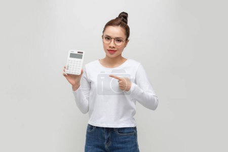 Foto de Concepto del día fiscal. Mujer confiada sonriendo sujeción calculadora y dedo dispositivo de punta - Imagen libre de derechos