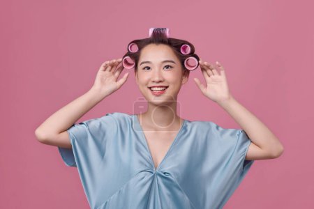 Foto de Imagen de una mujer joven con rizadores de pelo sobre fondo rosa - Imagen libre de derechos
