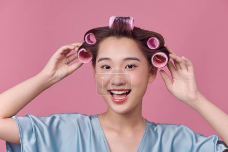 Téléchargez les photos : Gai asiatique fille avec cheveux bigoudis rouleaux par coiffeur. - en image libre de droit