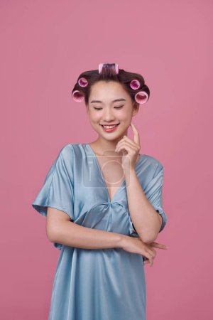 Photo for Cheerful young model posing with hair curlers on pink background - Royalty Free Image