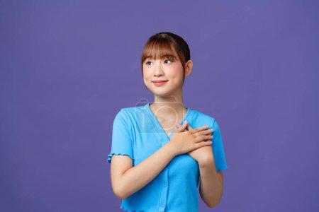 Photo for Cheerful woman smiling and holding hands on chest isolated over purple wall - Royalty Free Image