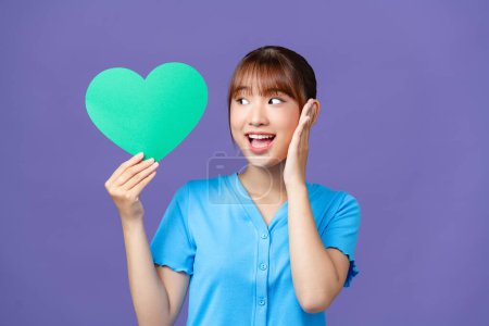 Photo for Cheerful young woman hold  green heart paper shape isolated on purple background - Royalty Free Image