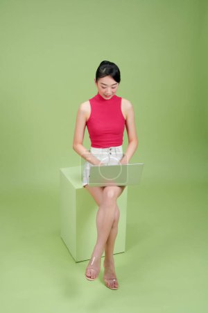 Foto de Chica joven con un ordenador portátil sentado en un taburete de la caja - Imagen libre de derechos