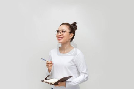 Téléchargez les photos : Portrait d'une chère jolie femme prenant des notes dans un bloc-notes sur blanc - en image libre de droit