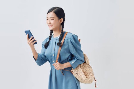 Foto de Portrait of smiling Asian woman using a smartphone isolated on white background - Imagen libre de derechos