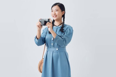 Téléchargez les photos : Jeune fille prenant une photo avec un petit appareil photo sur un fond blanc - en image libre de droit