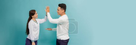 Téléchargez les photos : Joyful man and woman greeting each other with a high five isolated on blue banner - en image libre de droit