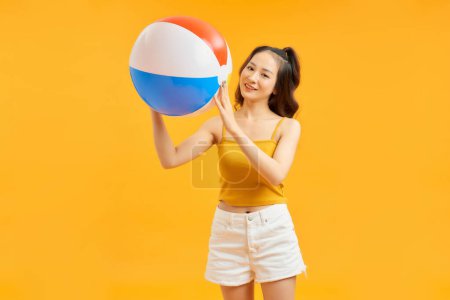 Photo for Young asian woman holding beach ball isolated on vivid yellow background happy - Royalty Free Image