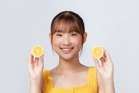 Foto de Retrato de una hermosa mujer joven con limón fresco cerca de la cara sobre fondo blanco. - Imagen libre de derechos