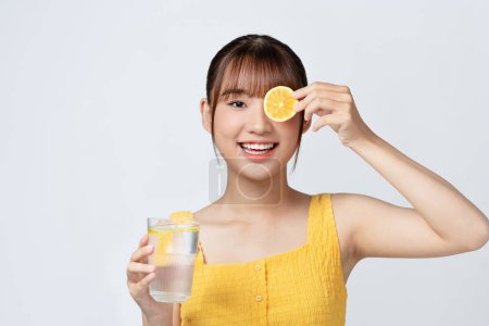 Téléchargez les photos : Jeune femme avec un verre d'eau de citron sur fond blanc - en image libre de droit