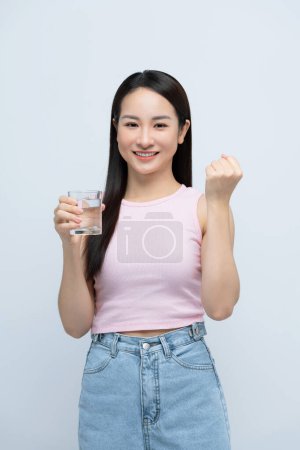 Foto de Asiática mujer bebiendo vaso de agua gritando orgulloso, celebrando la victoria con el brazo levantado - Imagen libre de derechos