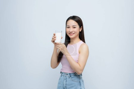 Foto de Joven sonriente feliz divertido mujer celebrar en la mano vaso beber leche aislada sobre fondo blanco. - Imagen libre de derechos