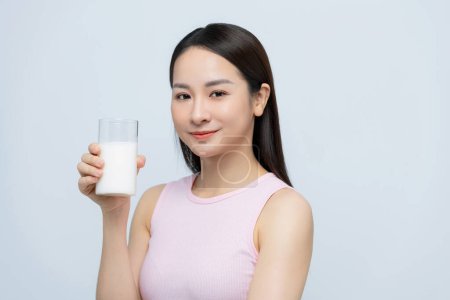 Foto de Retrato joven mujer asiática bebiendo leche del vaso aislado sobre fondo blanco - Imagen libre de derechos