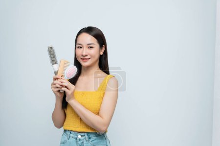 Foto de Asiático mujer holding hairbrushes cerca de cara - Imagen libre de derechos