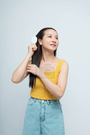 Photo for Portrait of a beautiful black-haired woman holding comb in her hand on white background. - Royalty Free Image