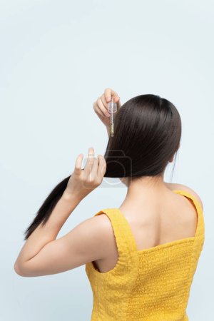 Foto de Mujer aplicando aceite hidratante a su cabello rizado, - Imagen libre de derechos