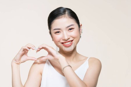 Foto de Feliz hermosa mujer asiática hacer corazón con las manos cerca de su cara - Imagen libre de derechos