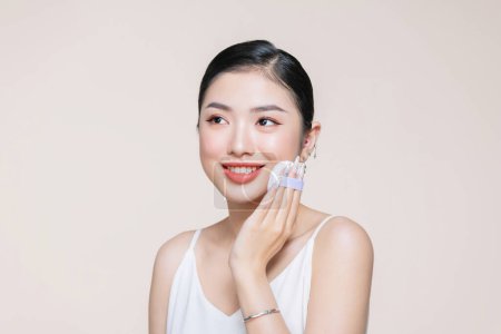 Téléchargez les photos : Asiatique femme sourire recherche heureux application maquillage avec bouffée maquillage à son visage - en image libre de droit