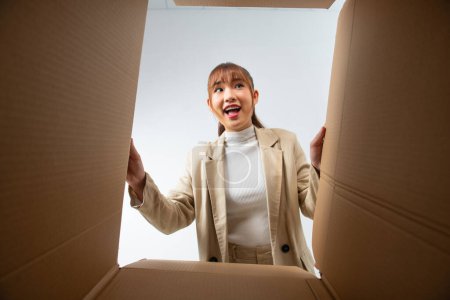 Photo for A young woman opens up a box, surprised and happy to see their order better than expected - Royalty Free Image
