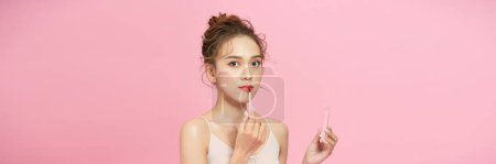 Foto de Atractivo y hermoso chica asiática pintar los labios un lápiz labial rosa - Imagen libre de derechos