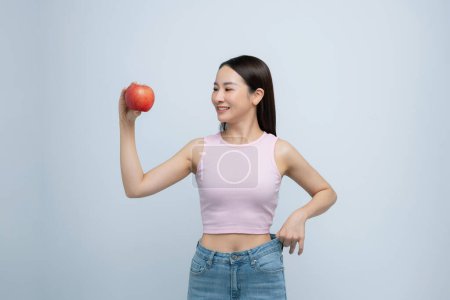 Photo for Pretty girl in jeans are big, holds an apple in her hand. - Royalty Free Image