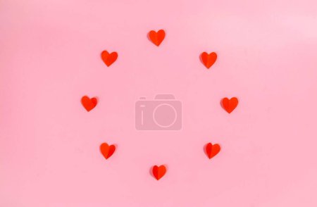 Foto de Red paper hearts arranged in a circle. Happy Valentine's Day greeting card. Love time. Copy space. Flat lay. Template for text or design. - Imagen libre de derechos