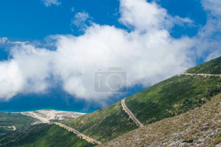 Niebla blanca en lo alto de las montañas en el paso Llogara. Vista desde las tierras altas en camino serpenteante hacia el paso.Paisaje de la Riviera albanesa, playa de Palasa y nubes blancas contra un cielo azul. Albania.