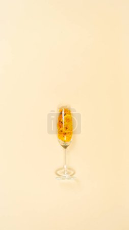 Photo for Glass with orange marigold flowers and splashing petals. Light yellow background. Holiday, nature or women's day concept. Copy space. - Royalty Free Image