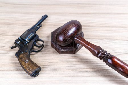 Foto de Martillo de madera ceremonial del juez en un soporte junto a la pistola. Concepto legislativo y jurídico. Copiar espacio. - Imagen libre de derechos