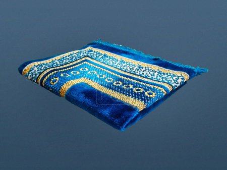Folded Muslim prayer mat used to pay on dark background