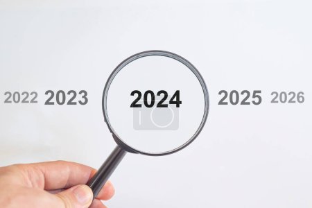 Photo for Year 2024 in a magnifying glass.past and future years.new year idea concept.preparing for new job. - Royalty Free Image