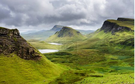 Téléchargez les photos : Beau paysage de montagne écossais spectaculaire, Skye, sommets escarpés, route sinueuse et falaises escarpées, le long des collines de Quiraing, herbe verte couverte au milieu de l'été, dans le nord-est. - en image libre de droit