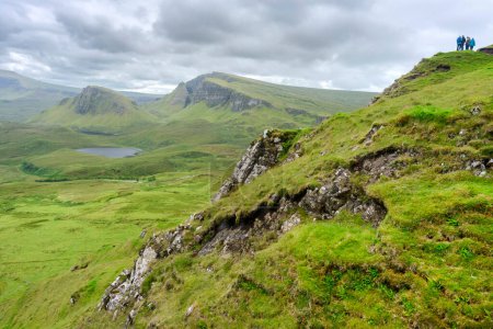 Foto de Quiraing, Isla de Skye, Escocia, Reino Unido-25 de julio de 2022: Los excursionistas caminan a lo largo de los senderos de montaña de la cordillera del Quraing, en un día de verano, tomando el camino de abajo y vistas espectaculares y panorámicas.. - Imagen libre de derechos