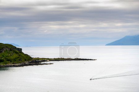 Téléchargez les photos : Petit canot dérivant à travers la surface calme du Loch vers le rivage, milieu de la saison estivale. - en image libre de droit