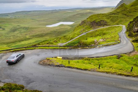 Photo for Mountain road for traffic visiting the Quiraing walking trail,amongst beautiful dramatic scenery,winding down to the coast,on a rainy mid summer day.north east of Skye. - Royalty Free Image