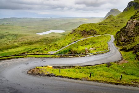 Photo for Mountain road for traffic visiting the Quiraing walking trail,amongst beautiful dramatic scenery,winding down to the coast,on a rainy mid summer day.north east of Skye. - Royalty Free Image