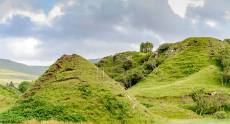 Téléchargez les photos : Château comme basalte rocheux proéminence, avec de belles vues sur les environs, collines en forme de cône et monticules, un paysage mignon, surréaliste, fantasme comme, herbe couverte. Un site touristique populaire près d'Uig sur Skye. - en image libre de droit