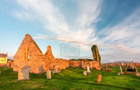 Photo for Magical historic landmark near Durness,founded 8th Century,important Celtic monastery,ancient gravestones and graveyard,grass covered,dramatic sunset sky,at Balnakeil Bay,eerie atmosphere at dusk. - Royalty Free Image