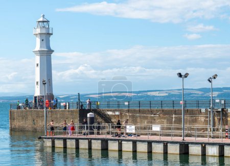 Téléchargez les photos : Édimbourg, Écosse-30 juillet 2022 : Été sur le quai, à côté du phare de Newhaven, les visiteurs pêchent, jouent ou observent les eaux tranquilles et calmes, par un après-midi calme, chaud et ensoleillé. - en image libre de droit