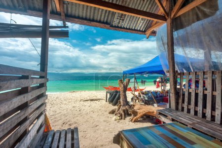 Photo for Viewed from within a shaded seating area,next to a drinks seller.A lazy,chilled out idyllic beach in the Philppine islands,with white,fine sand,clear blue sea,clean,un-polluted,serene and relaxing. - Royalty Free Image