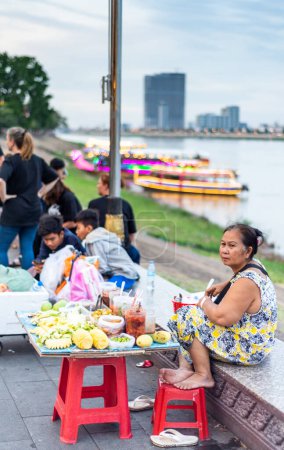 Photo for Phnom Penh,Cambodia-January 4th 2023: Food vedors wait for passing trade,while socializing,as the relative cool of the day arrives,after sunset. - Royalty Free Image