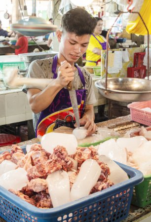 Téléchargez les photos : Île Cebu, Philippines - 27 janvier 2023 : En utilisant l'extrémité pointue d'une lame de coupe de viande, l'homme brise la glace pour la mélanger à de la viande de porc crue, en vente dans un marché alimentaire de l'après-midi. - en image libre de droit